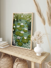 Illustrative water lily pond print with white water lilies, green lily pads, and tall reeds, in an alternate framed mockup