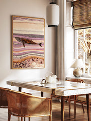 Indigenous style dot art print of a whale swimming horizontally amidst abstract purple and, in a styled room mockup