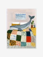 Illustrative whale wall art print showing a blue whale on a colorful patchwork quilt in a bedroom with a yellow nightstand.