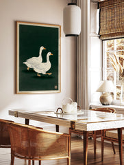 Two white geese with orange beaks and feet walking on a dark green background in a Japanese, in a styled room mockup