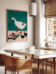 Illustrative print of a large white goose walking, three black ducks, and a tray of food on a pink, in a styled room mockup