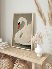 White swan woodblock style art print with red and black beak, on sage green background, in an alternate framed mockup