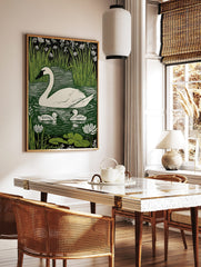 White swan and two cygnets on green water with reeds and white flowers in linocut print style, in a styled room mockup