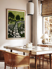 Illustrative garden print with winding stone path, white wildflowers, and dark trees against a, in a styled room mockup