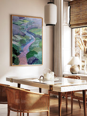 Illustrative landscape art print with a winding pink brick path, blue river, and green and purple, in a styled room mockup