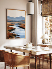 Watercolour landscape art print of a winding river through orange marshland with blue mountains in, in a styled room mockup
