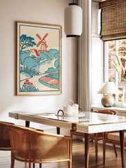 Vintage-style illustrative print featuring a red windmill, cottage, arched bridge, and red flowers, in a styled room mockup