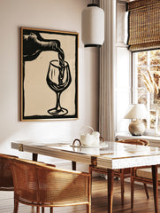 Linocut style black and white wall art of wine pouring into a glass on a neutral background, in a styled room mockup
