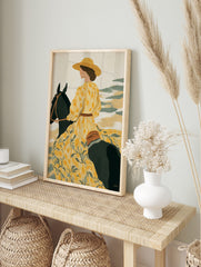 Illustrative art print of a woman in a yellow floral dress and hat riding a dark horse, in an alternate framed mockup