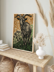 Woodcut style print of a ram goat with large horns in grass and flowers, brown and green, in an alternate framed mockup