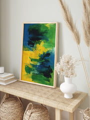 Abstract painting with bold blue, green, and yellow brushstrokes on canvas, creating a, in an alternate framed mockup