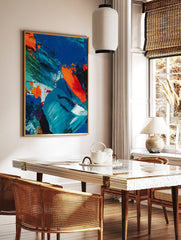 Abstract painting with textured blue, orange, and green impasto brushstrokes on canvas, in a styled room mockup