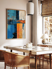 Abstract art print with textured blocks of blue, orange, white, and dark tones in a grid-like, in a styled room mockup