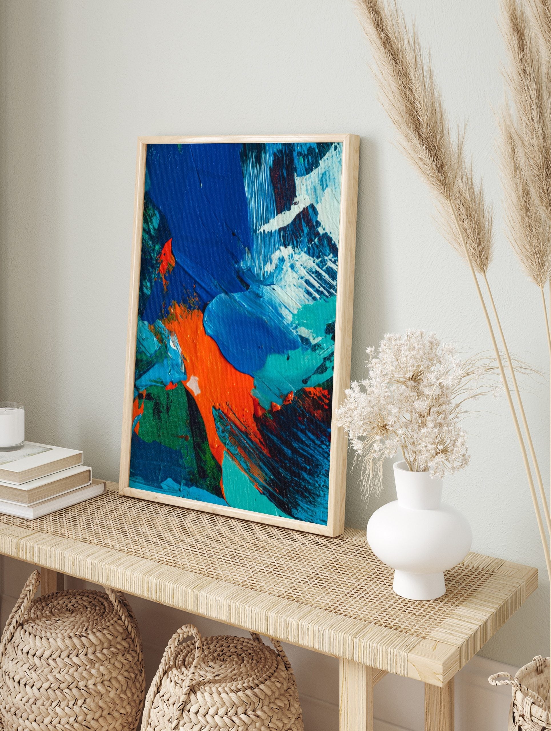 Close-up of abstract painting with textured blue, orange, green, and white paint strokes, in an alternate framed mockup