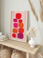 Abstract botanical wall art with red, orange, fuchsia, and purple rounded organic shapes on, in an alternate framed mockup