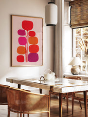 Abstract botanical wall art with red, orange, fuchsia, and purple rounded organic shapes on light, in a styled room mockup