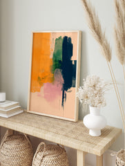 Abstract art print with vertical brushstrokes in orange, green, navy, and pink on a pale, in an alternate framed mockup
