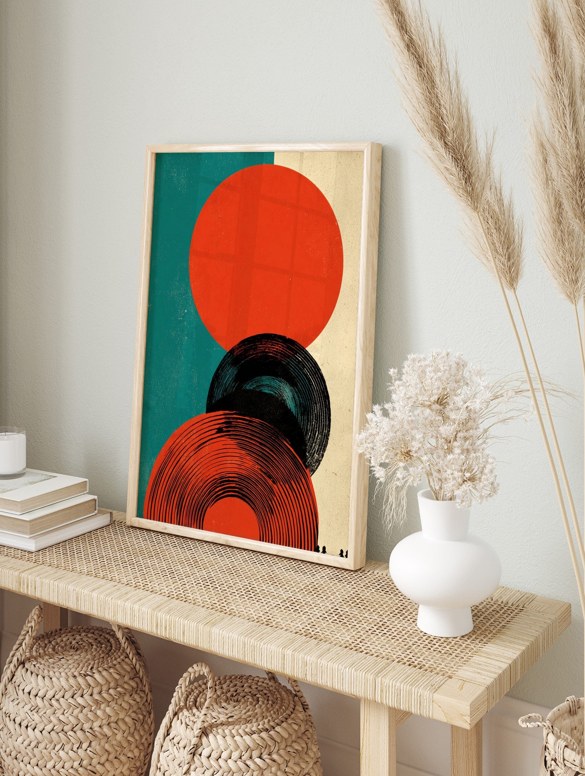 Abstract circles graphic print featuring orange-red and black concentric shapes on teal and, in an alternate framed mockup