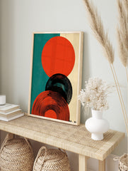 Abstract circles graphic print featuring orange-red and black concentric shapes on teal and, in an alternate framed mockup