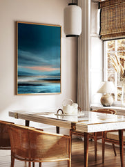 Abstract coastal landscape painting with dark blue sky, pink horizon, and textured blue, white, in a styled room mockup