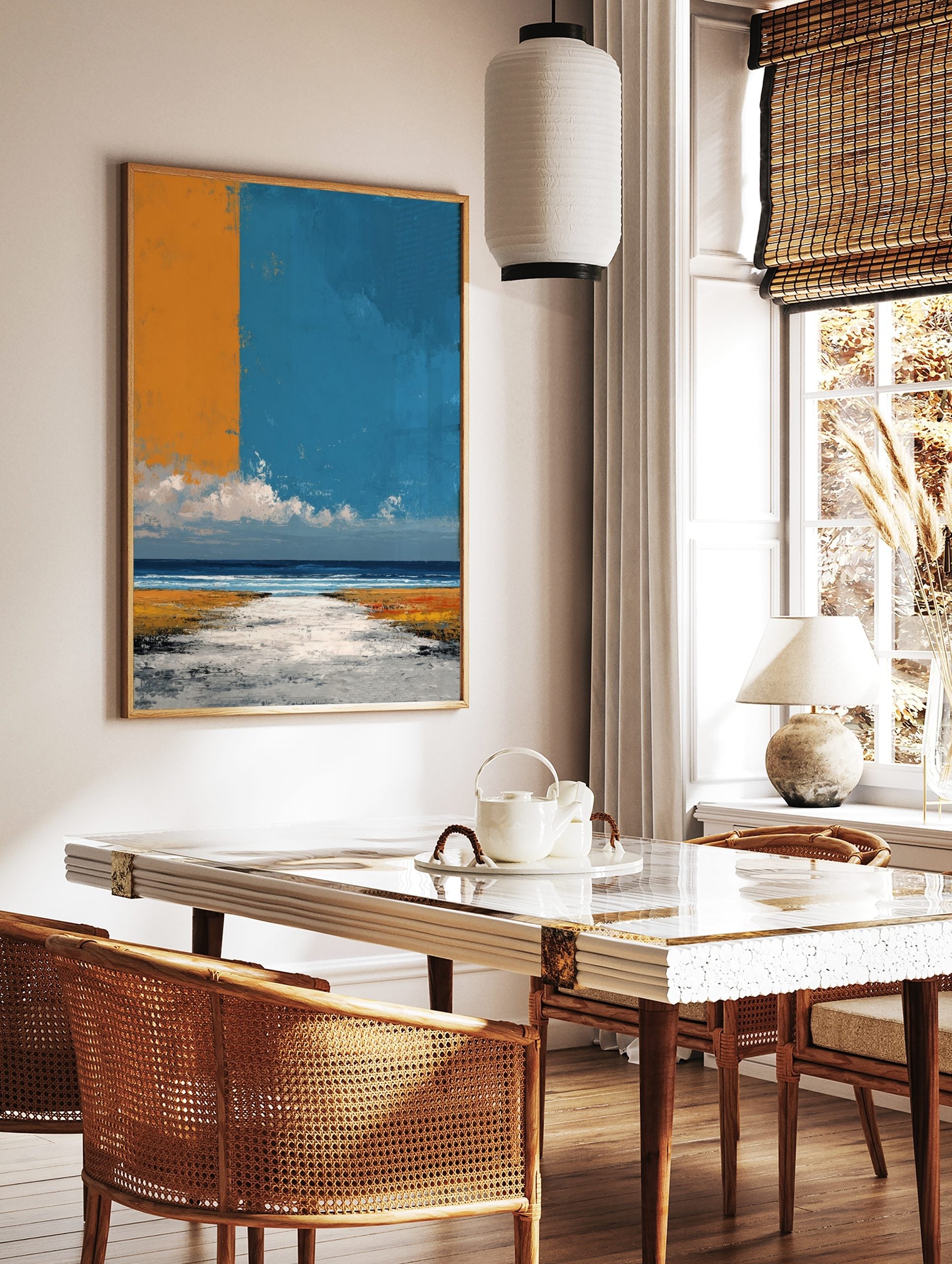 Abstract coastal landscape art print with orange and blue sky over a textured beach and ocean, in a styled room mockup