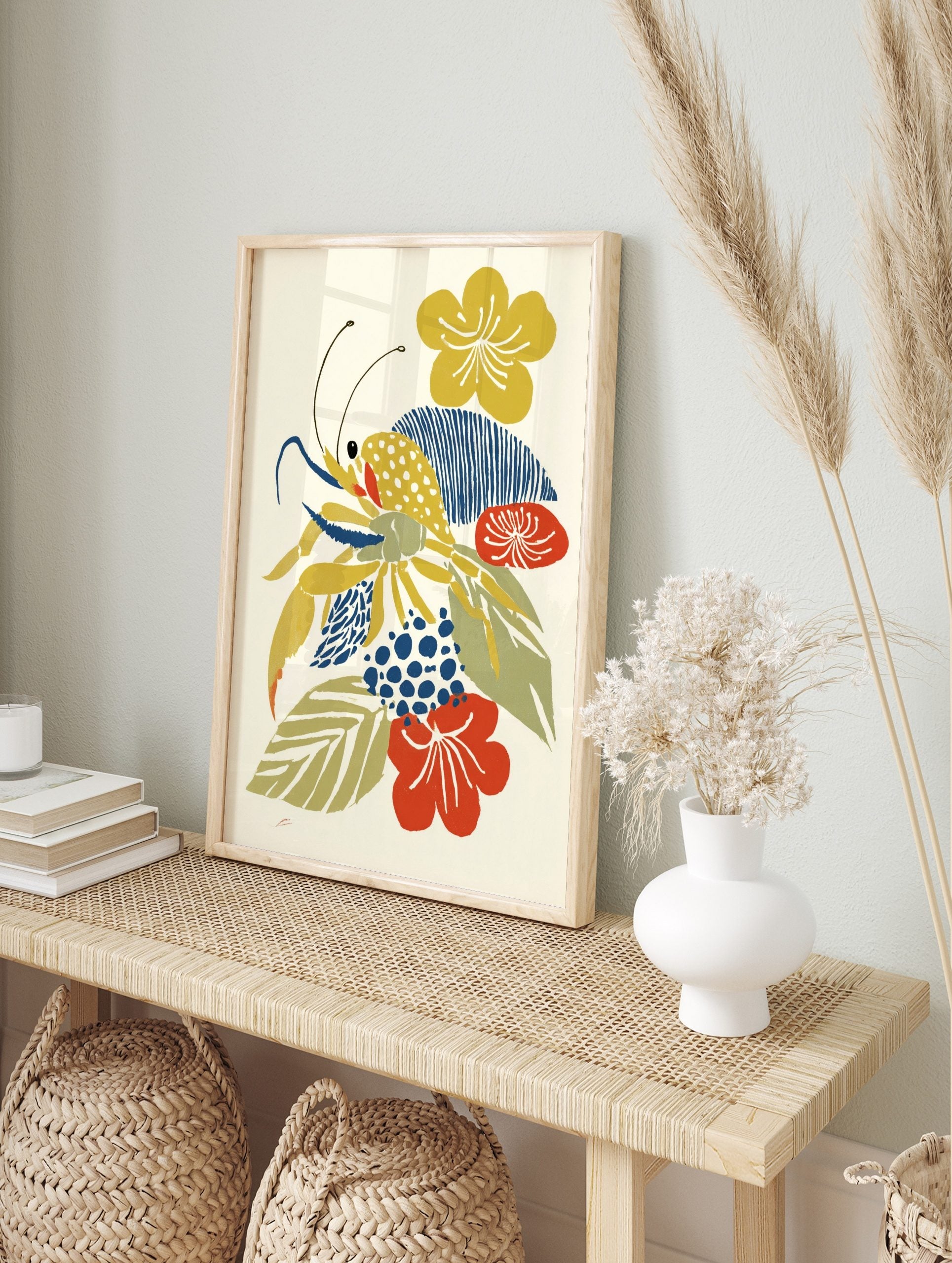 Abstract illustrative print of a yellow crab with blue claws and antennae, surrounded by, in an alternate framed mockup