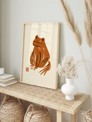 Abstract orange frog art print with painterly brushstrokes on a neutral background, in an alternate framed mockup