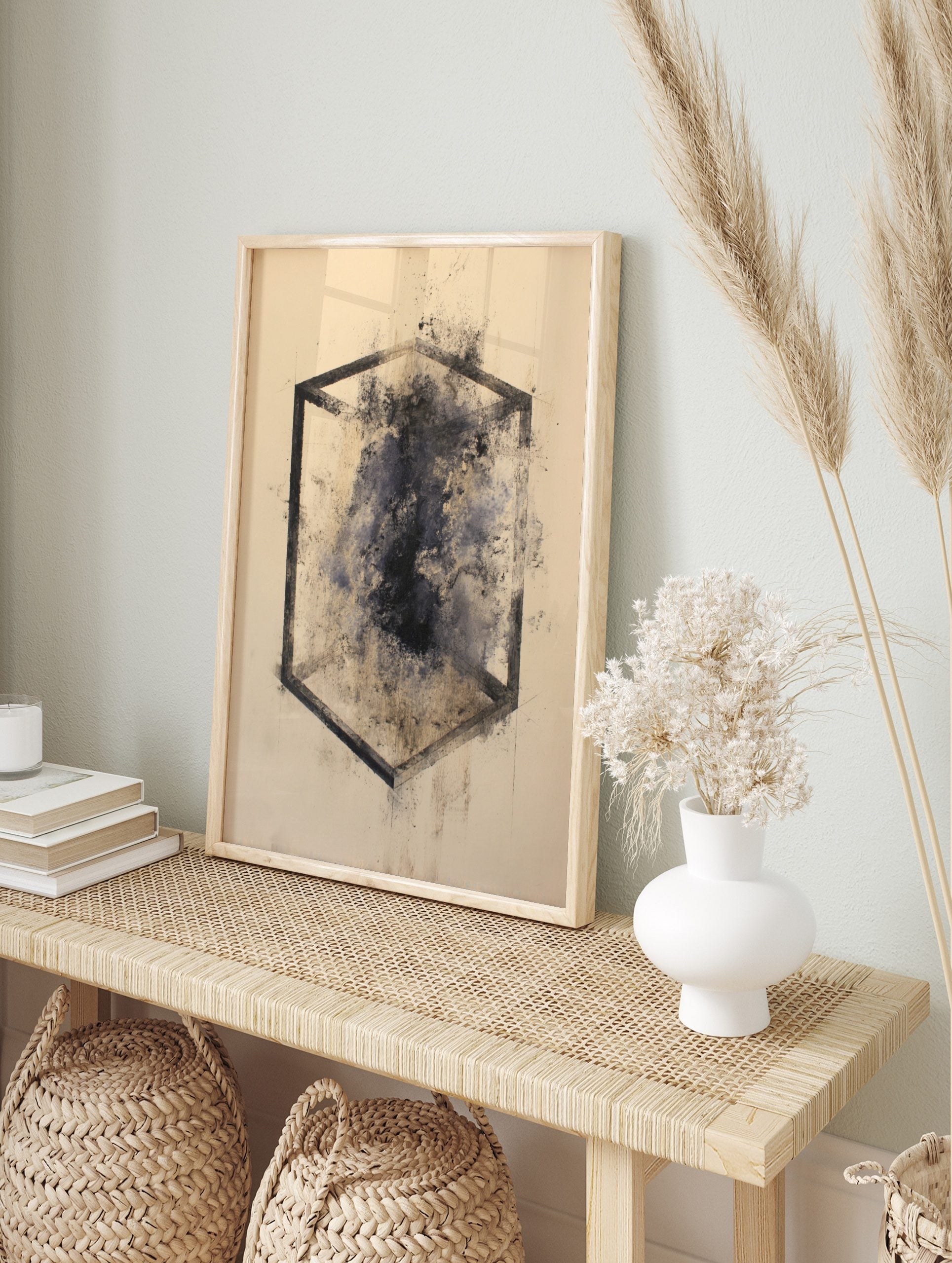 Abstract geometric cube outline with dark, smudged ink and speckles on a light background, in an alternate framed mockup