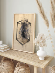 Abstract geometric cube outline with dark, smudged ink and speckles on a light background, in an alternate framed mockup