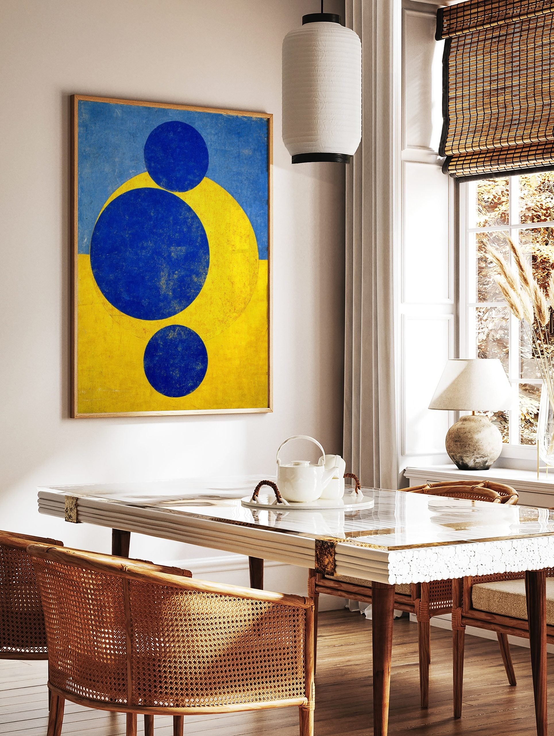 Abstract geometric art print with three blue circles and a yellow arc against a split blue and, in a styled room mockup