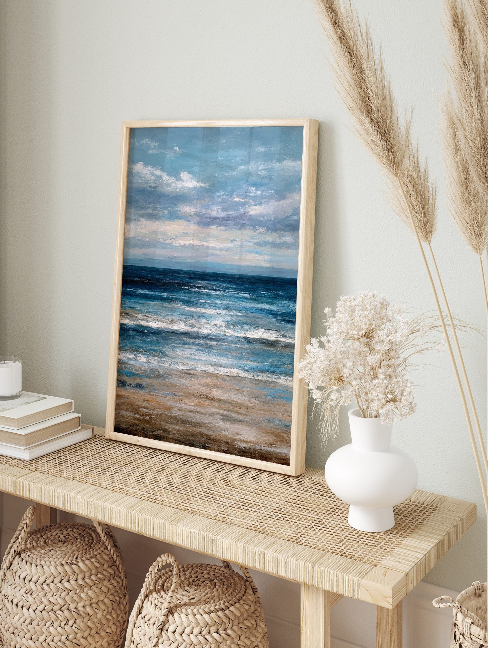 Abstract ocean beach scene wall art with deep blue waves, sandy shore, and cloudy blue sky, in an alternate framed mockup