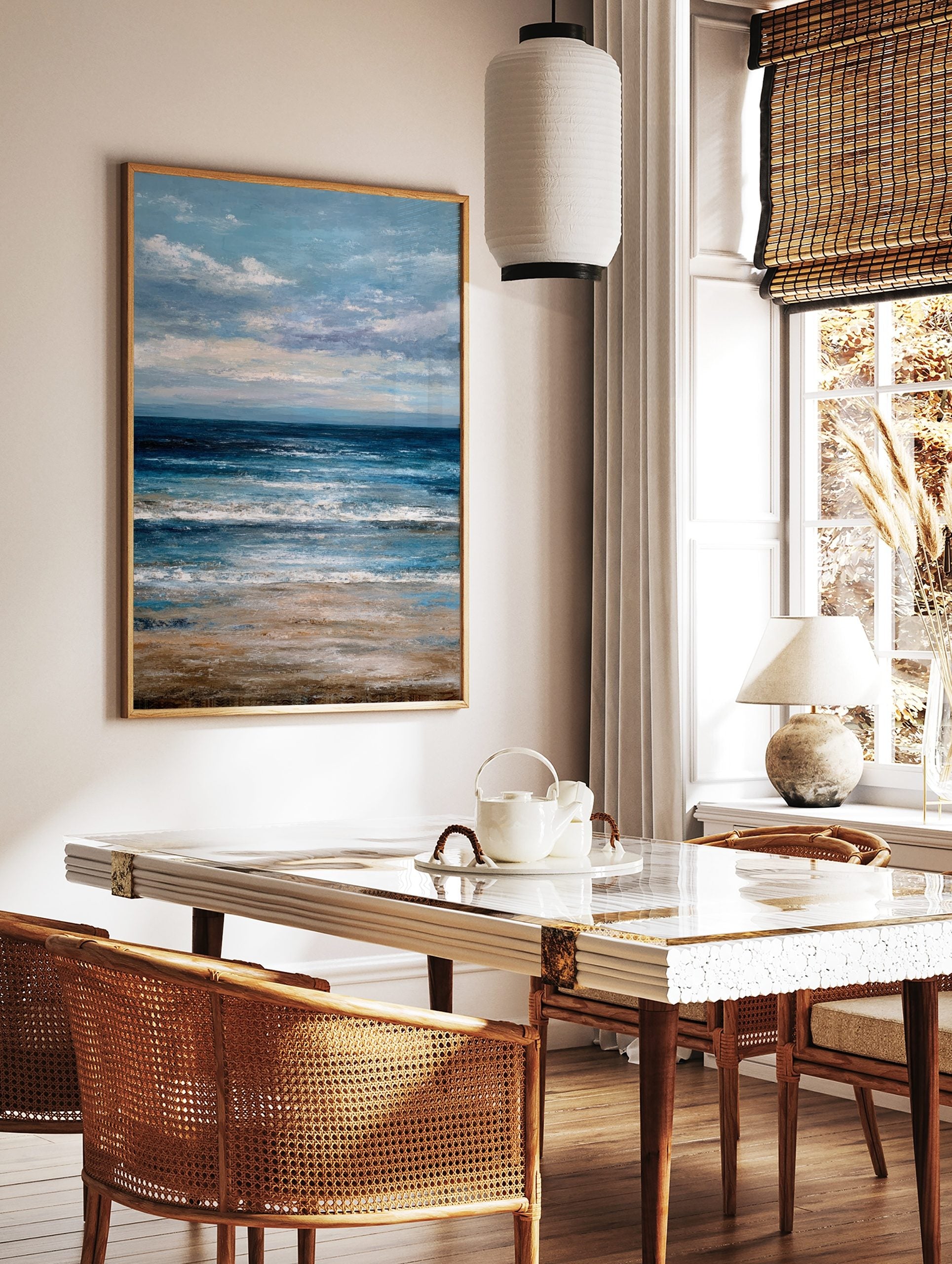 Abstract ocean beach scene wall art with deep blue waves, sandy shore, and cloudy blue sky, in a styled room mockup