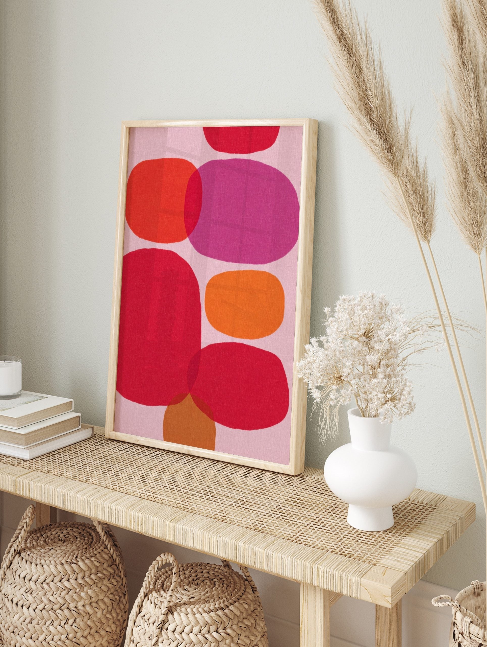 Abstract wall art print with overlapping organic shapes in pink, red, orange, and fuchsia on, in an alternate framed mockup