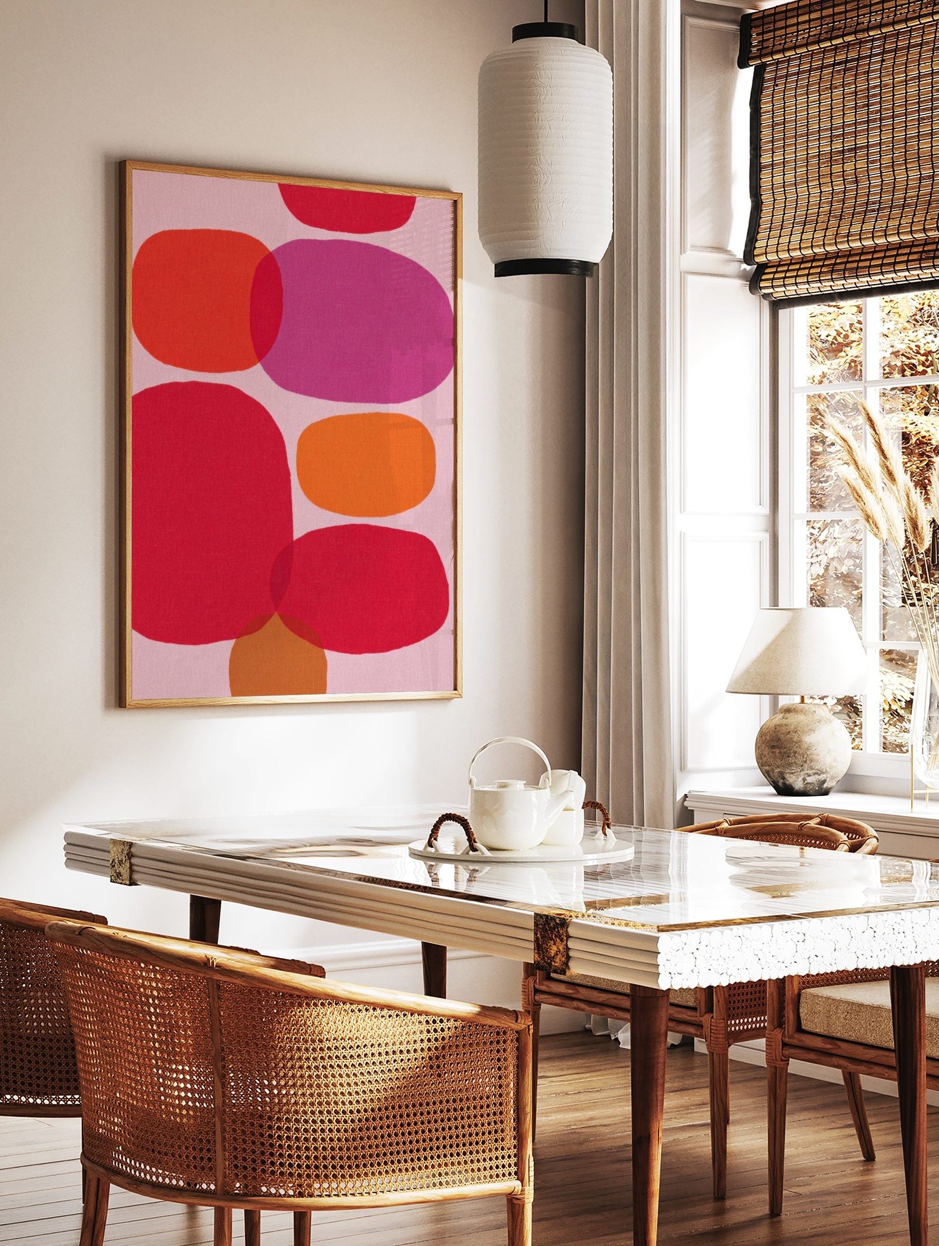 Abstract wall art print with overlapping organic shapes in pink, red, orange, and fuchsia on a pale, in a styled room mockup