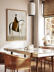Stylised abstract painting of a rider in brown and black cloak on a white horse, facing right on a, in a styled room mockup