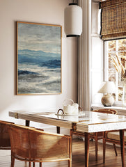 Abstract seascape painting with blue mountains, deep blue ocean, and textured white waves under a, in a styled room mockup
