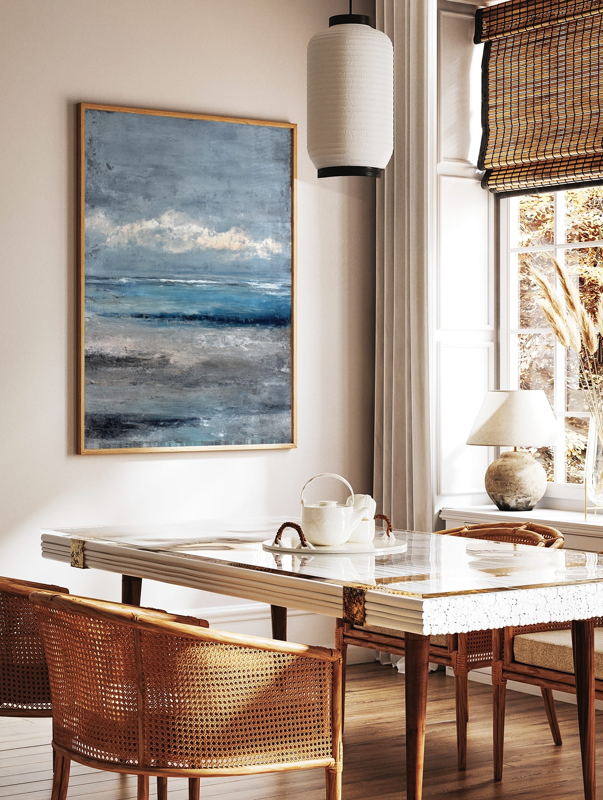 Textured abstract seascape painting with blue ocean, grey sky, and sandy beach in painterly style, in a styled room mockup