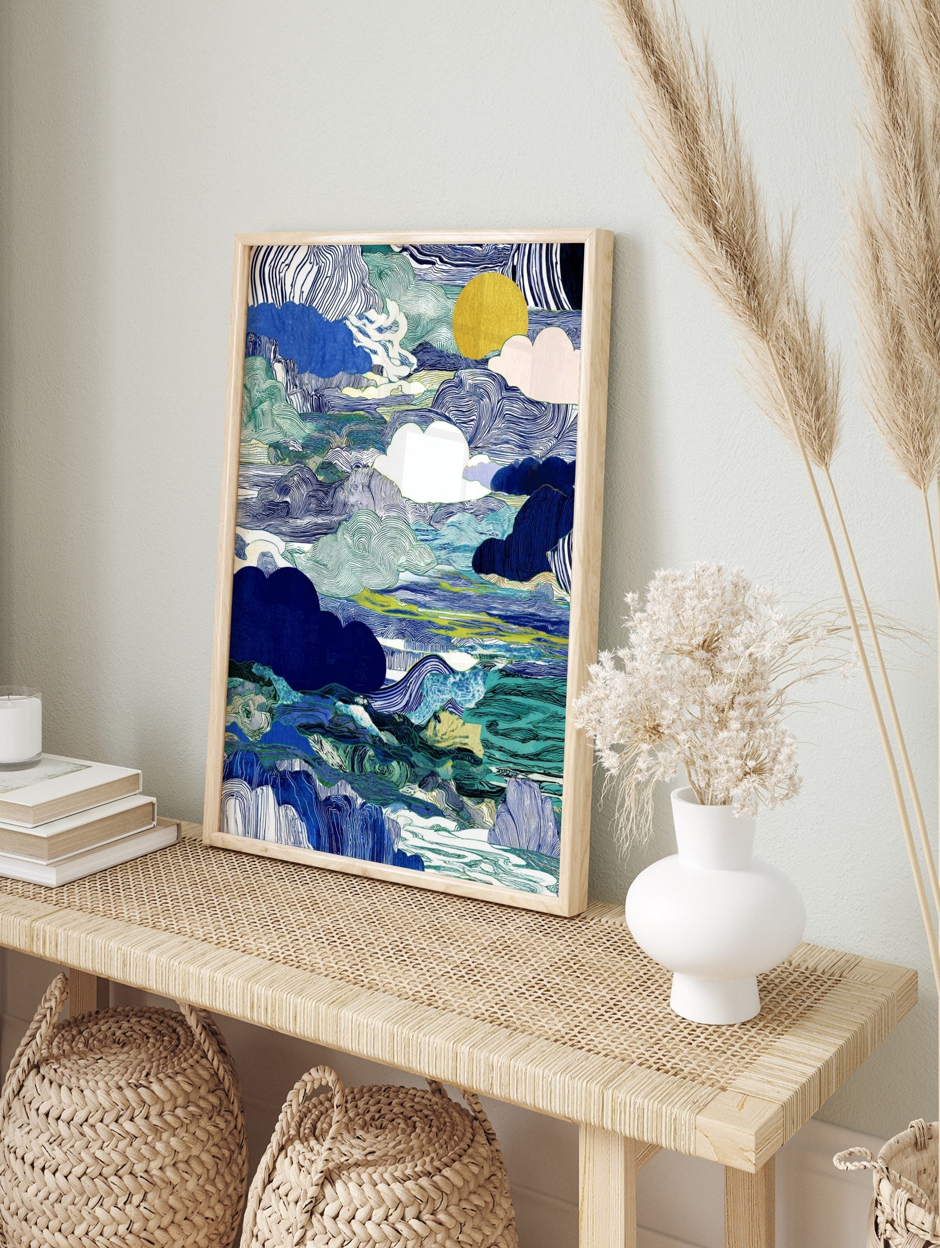 Abstract blue and green cloudscape wall art with wavy lines, solid clouds, and a golden sun, in an alternate framed mockup