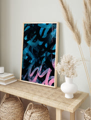 Abstract art print with bold teal and pink brushstrokes and splatters on a black background, in an alternate framed mockup
