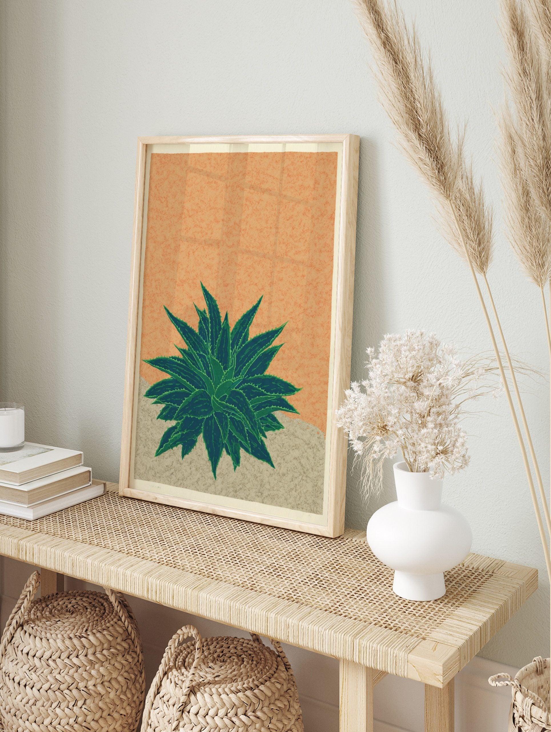 Illustrative agave plant print with spiky green leaves on a textured orange background and, in an alternate framed mockup