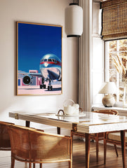 Modern airplane wall art print with a silver and red jet on a tarmac under a blue sky, featuring pink buildings. - Image 2