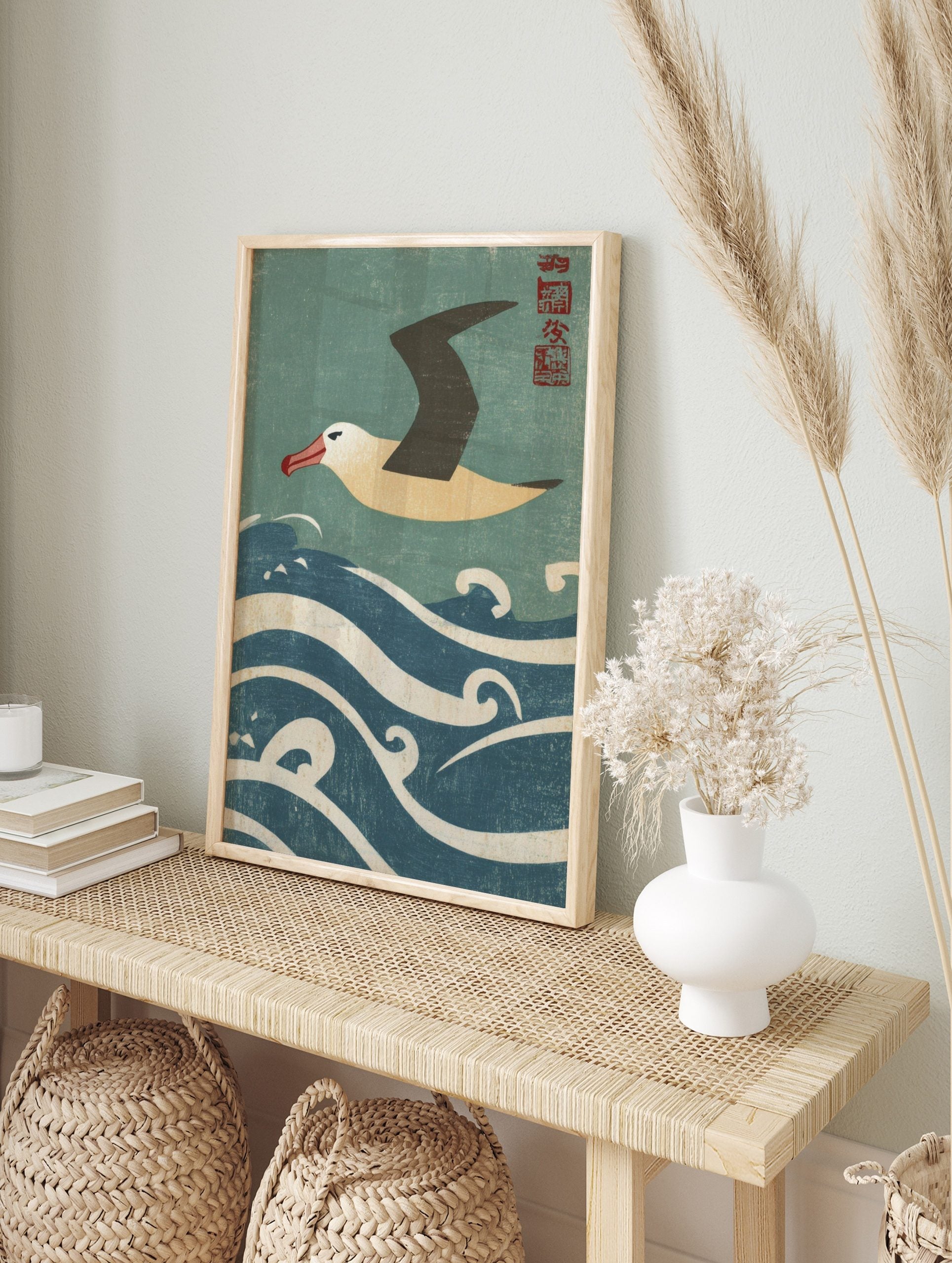 Japanese style albatross flying over blue and white waves with red kanji seal in the corner, in an alternate framed mockup