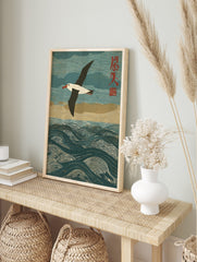 Albatross seabird flying over textured blue ocean waves with red Japanese characters in a, in an alternate framed mockup