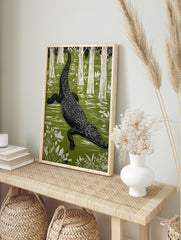 Linocut style alligator wall art swimming in a green swamp with white trees and plants in, in an alternate framed mockup