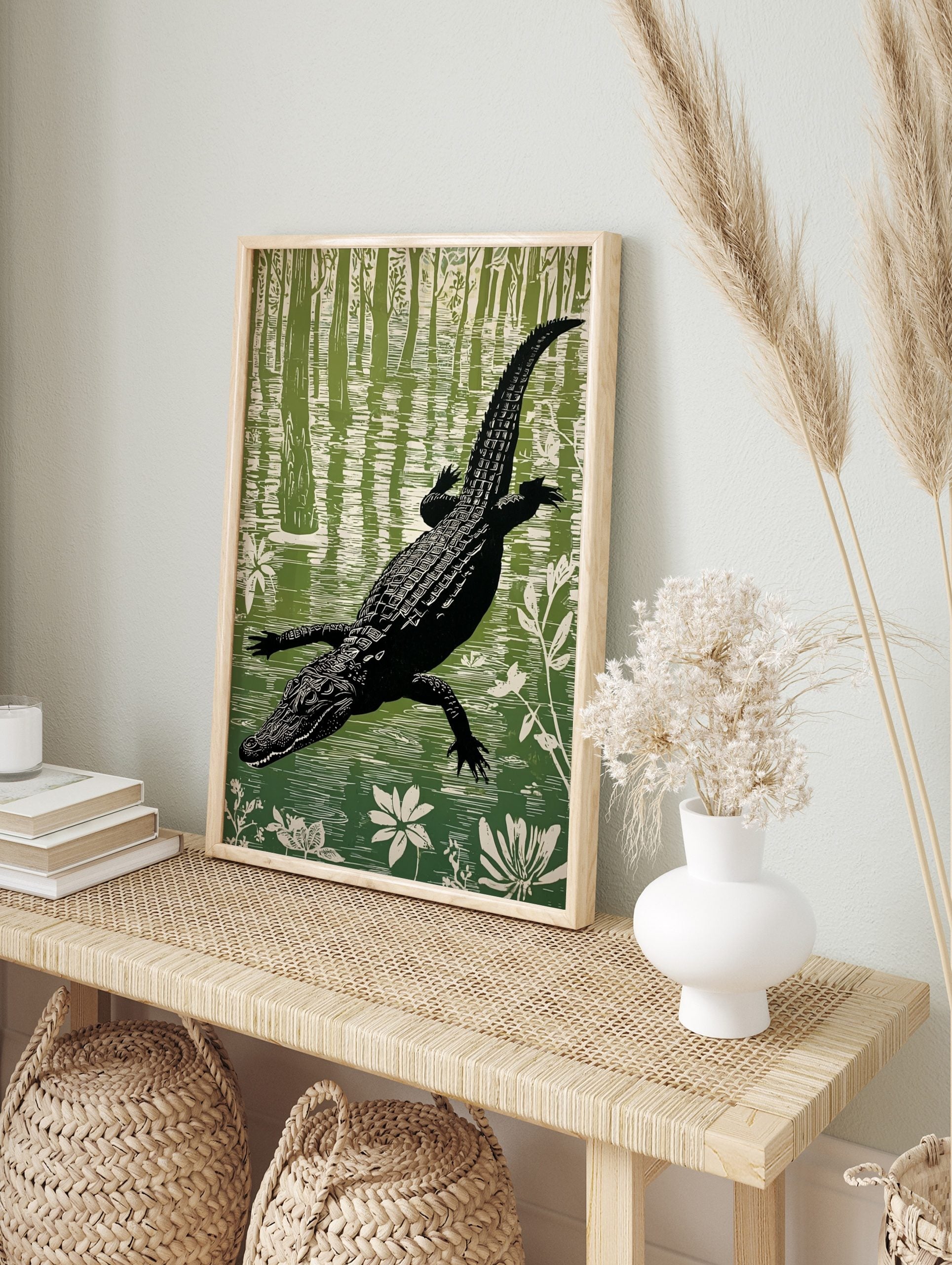 Illustrative linocut style print of a black alligator swimming in a green and white swamp, in an alternate framed mockup