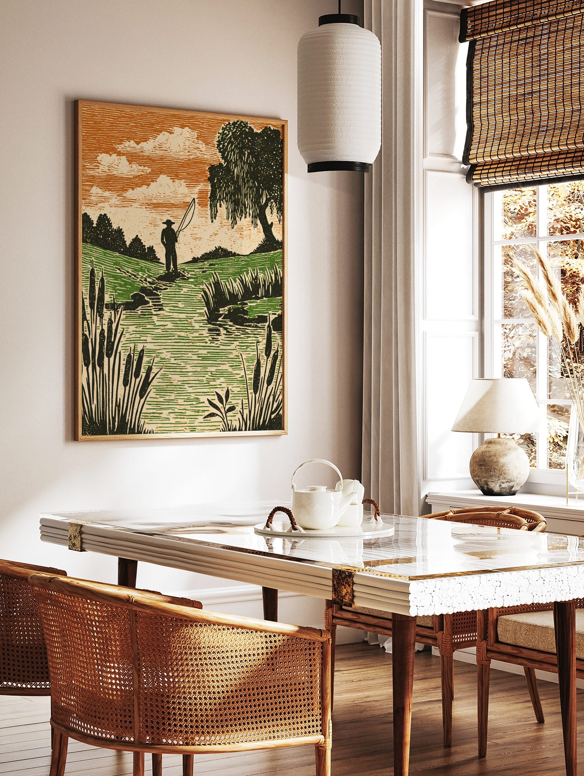 Woodcut style print of an angler fishing in a stream with green fields, orange sky, and cattails, in a styled room mockup