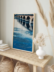 A blue water arch bridge poster featuring a stone bridge with multiple arches reflected in rippling water. - Image 4