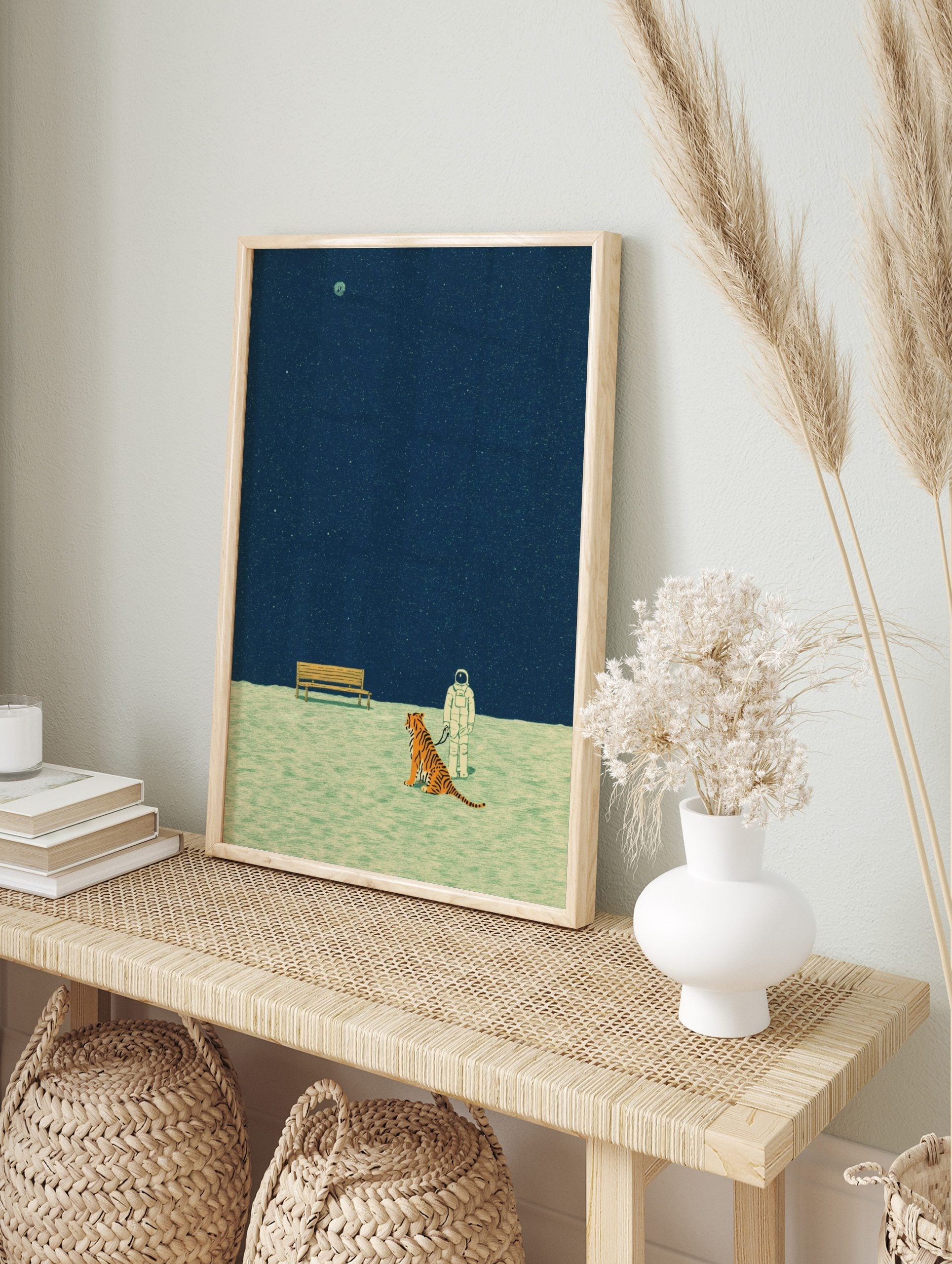 Illustrative print of astronaut on leash with tiger, wooden bench, dark blue starry sky, and, in an alternate framed mockup