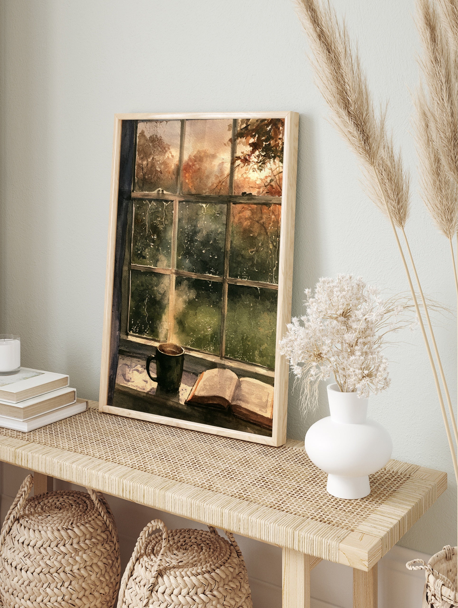 Watercolor painting of a steaming mug and open book on a windowsill looking out at rainy, in an alternate framed mockup