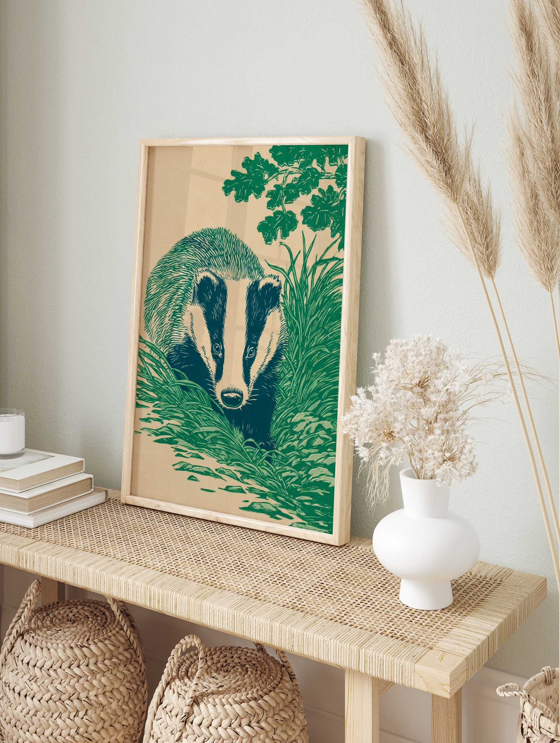 Illustrative linocut style print of a badger with striped face, hidden in green grass under, in an alternate framed mockup